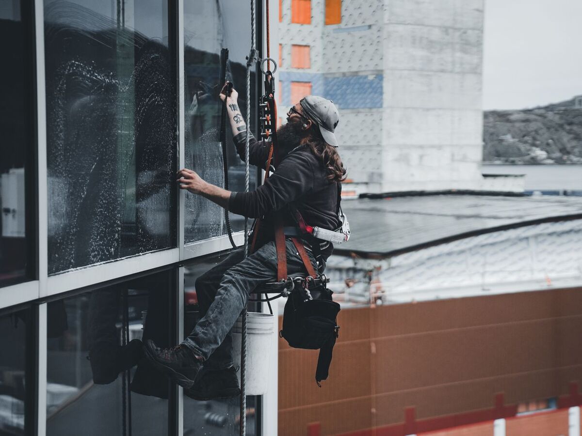 Window cleaner detailing commercial glass by hand