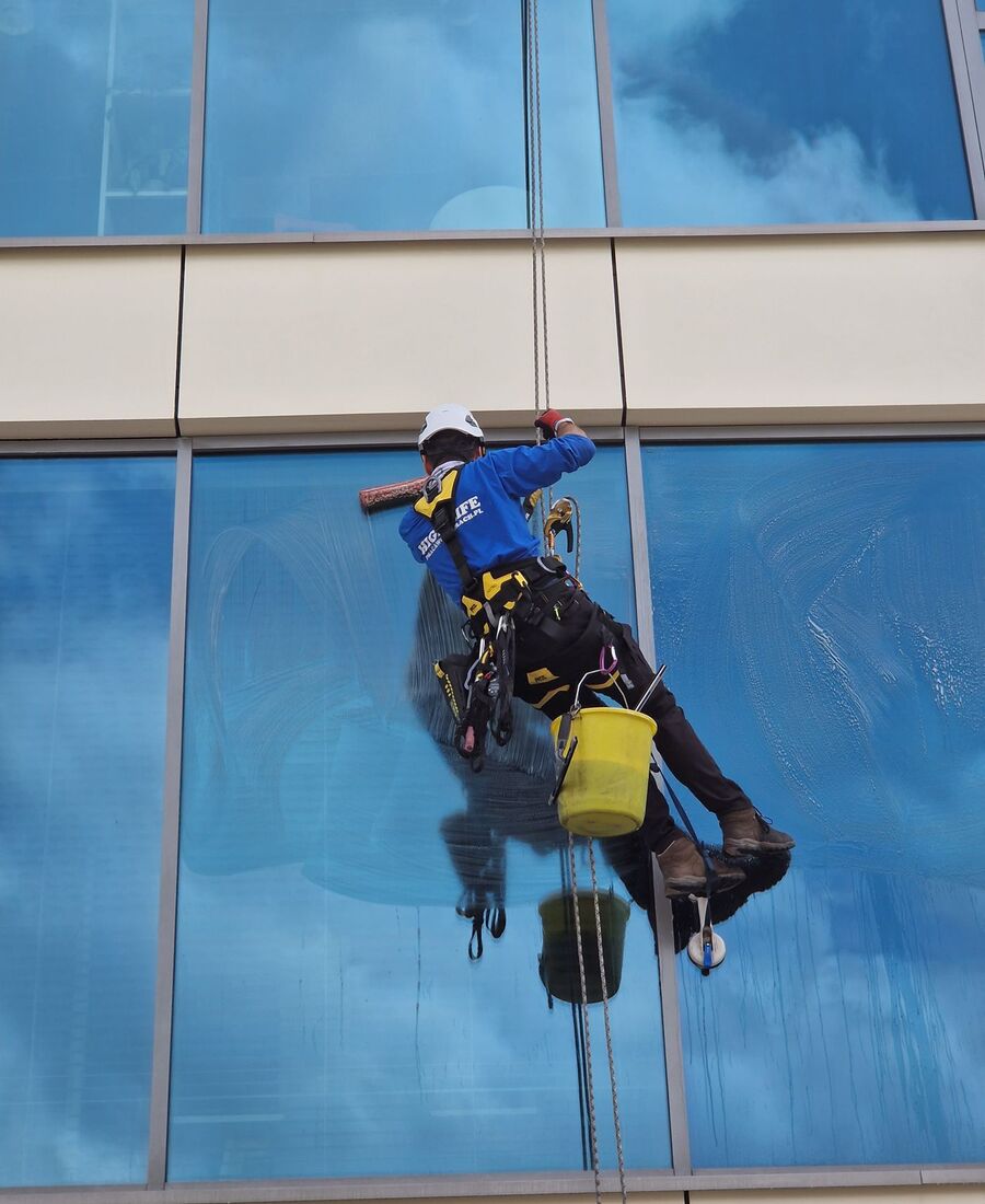 Window cleaner suspended on a glass curtain wall