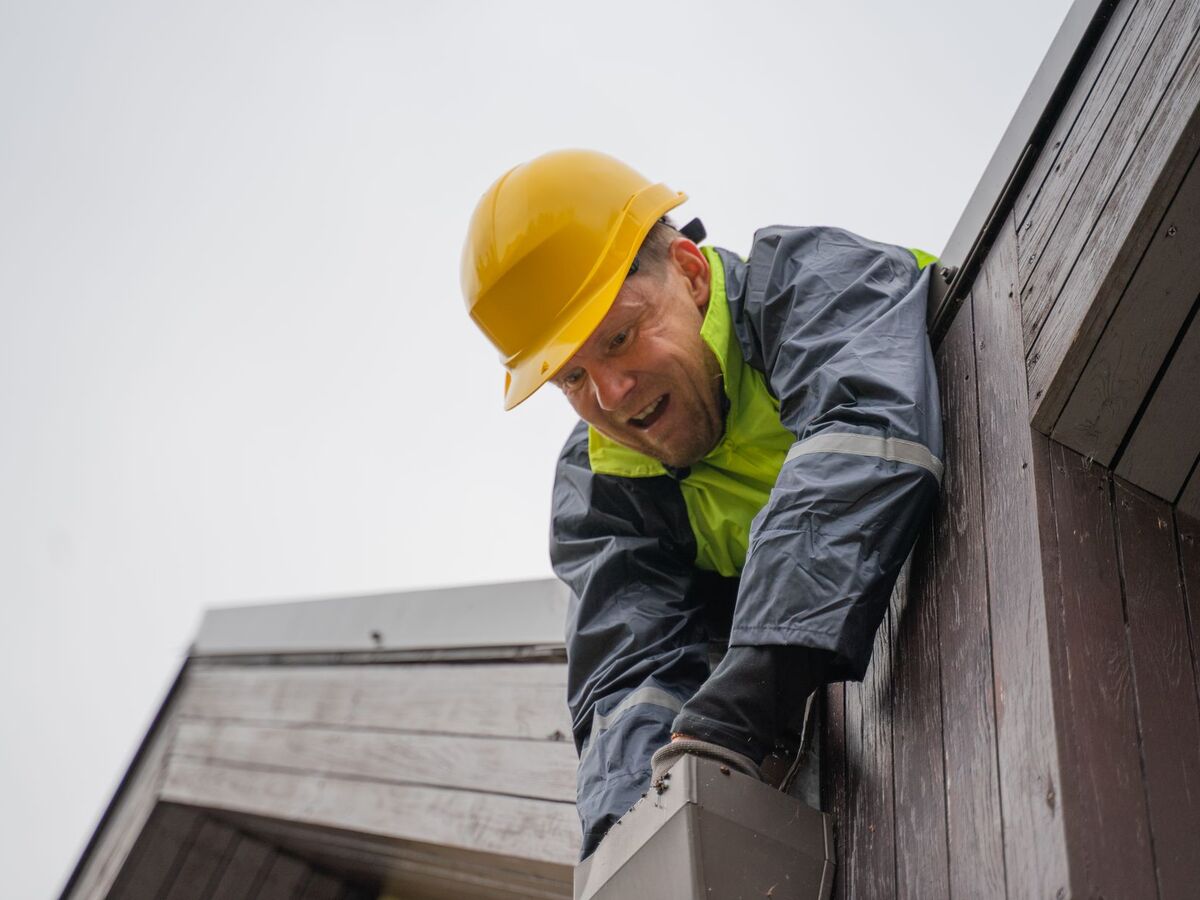Working along a roof edge to clear gutters